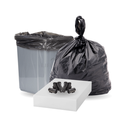 Black heavy-duty trash bag filled and tied, standing next to a trash bin
