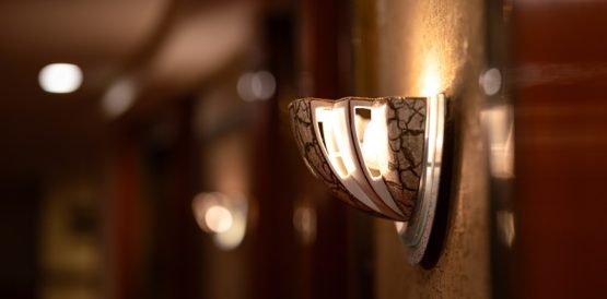 Modern wall sconce illuminating a clean motel guestroom.