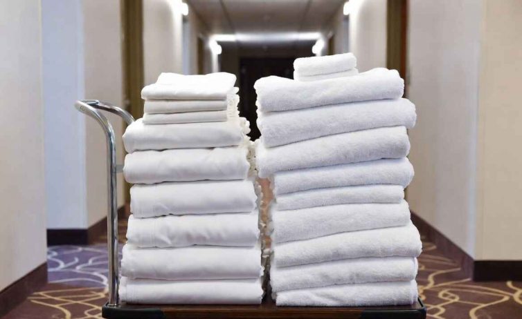 Housekeeping cart loaded with quality white linens and towels arranged strategically.
